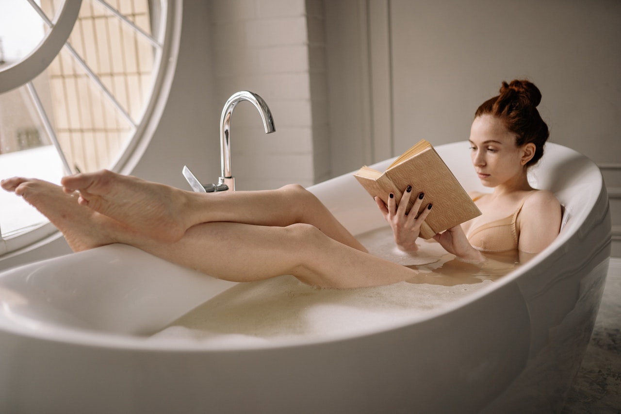 Self-care resolutions blog - woman reading book in bath