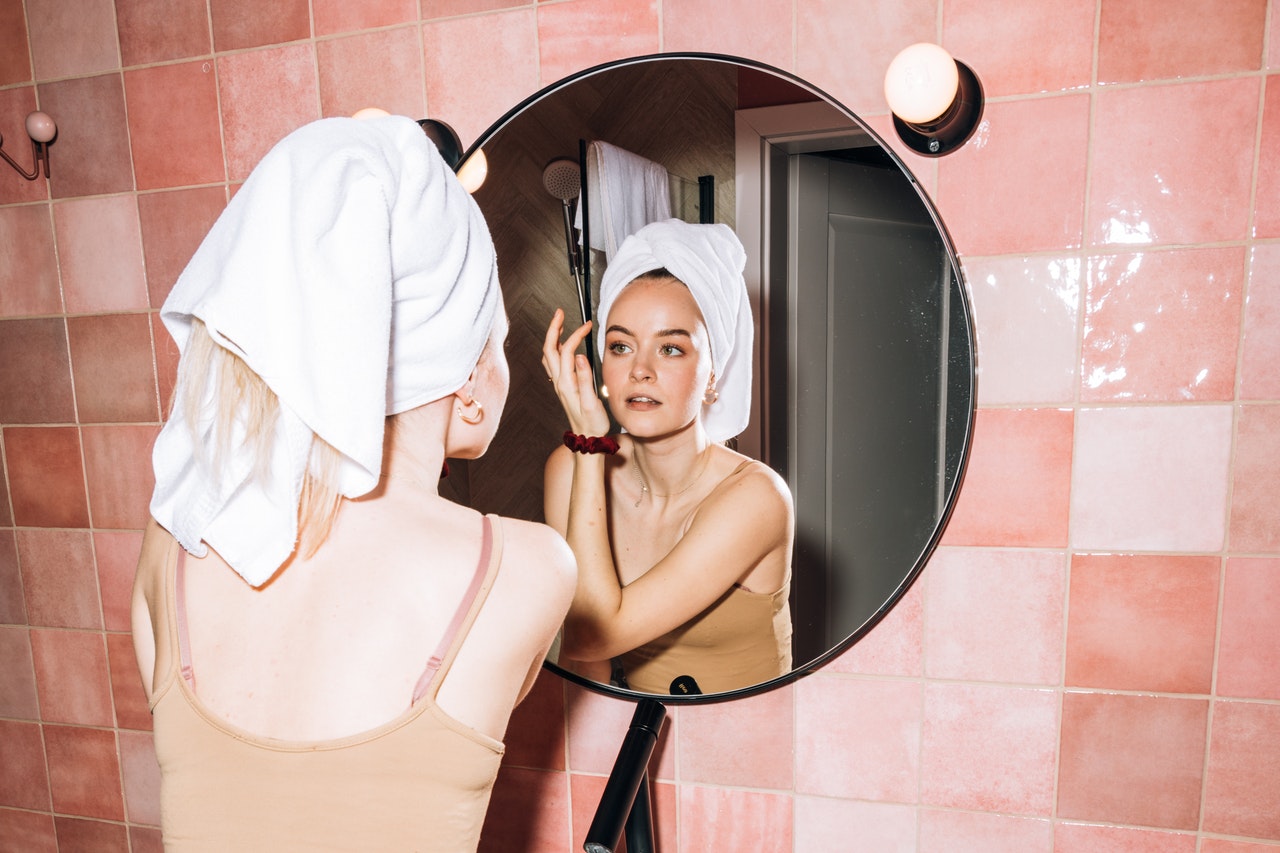 Woman looking at herself in the mirror in a pink tile bathroom
