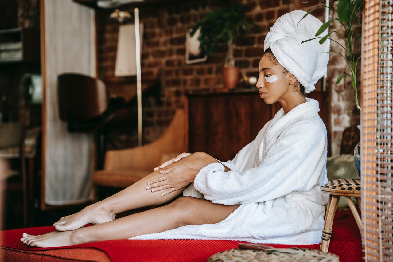 Girl sitting in robe and hair towel touching her legs
