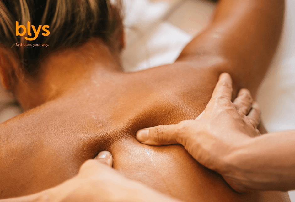 Close-up of a person receiving a relaxing remedial massage, with hands pressing the shoulders and upper back in a warm, soothing setting.