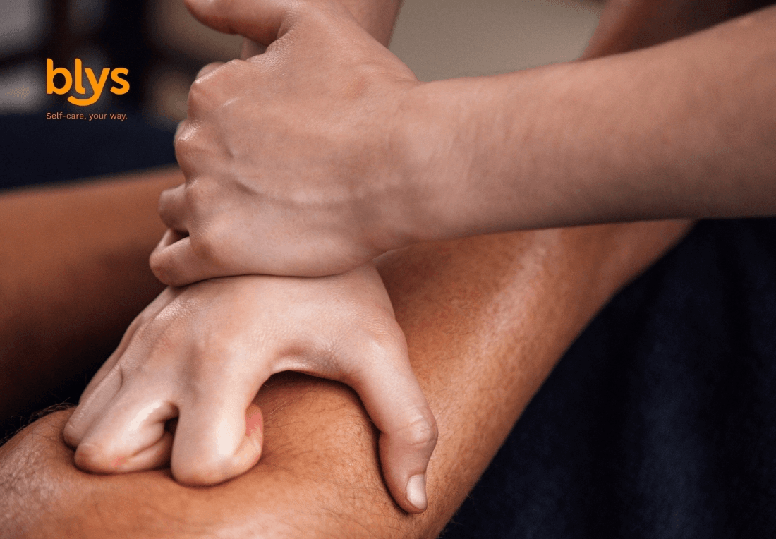 Close-up of hands applying firm massage pressure to a person, conveying relaxation, wellness, and therapeutic self-care; Blys logo visible.