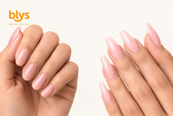 Two hands display glossy pink almond-shaped manicures; dip powder on the left and acrylic on the right, against a clean white background, with the orange “blys” logo in the corner.