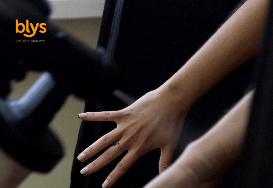 Close-up of a person’s outstretched hand and forearm against dark clothing receiving a spray tan; intimate, calm tone.