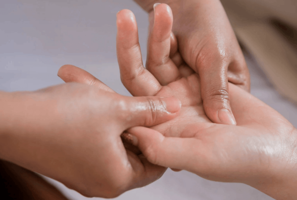 A close-up of two hands gently massaging another person’s hand and fingers for carpal tunnel and wrist pain, conveying a tender, caring moment of comfort and connection.