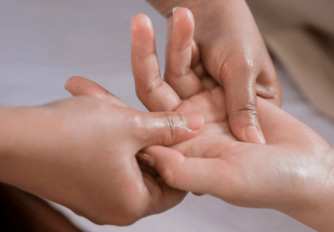 A close-up of two hands gently massaging another person’s hand and fingers for carpal tunnel and wrist pain, conveying a tender, caring moment of comfort and connection.